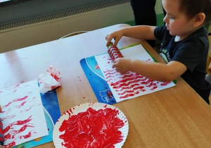 Chłopiec maluje wałkiem flagę biało-czerwoną